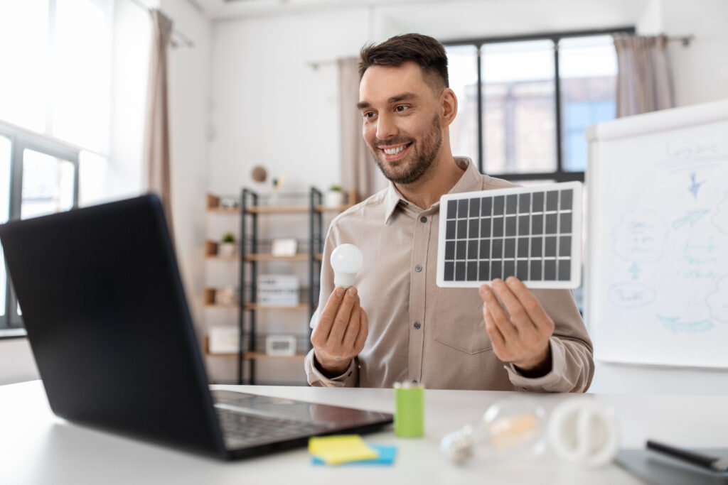 male teacher with laptop and solar battery at home